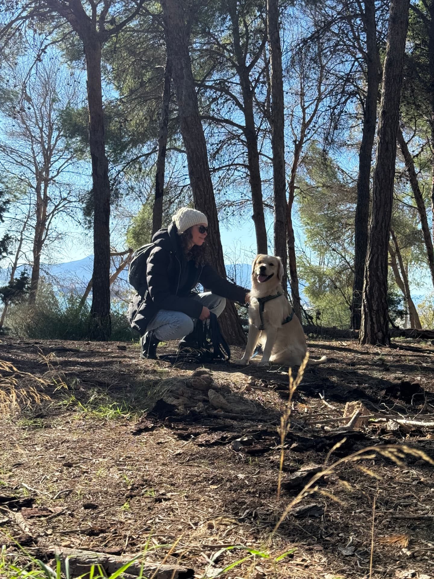 Mariana acariciando a Altivo, su golden retriever, en un pinar de Málaga
